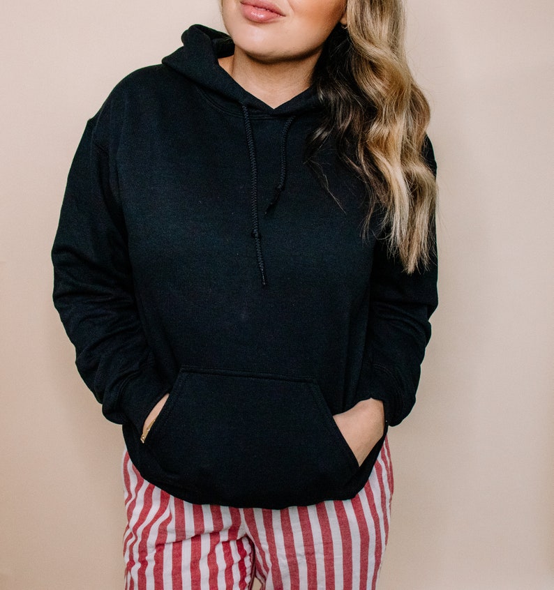 May include: A black hooded sweatshirt with a kangaroo pocket. The sweatshirt is worn over red and white striped pants.