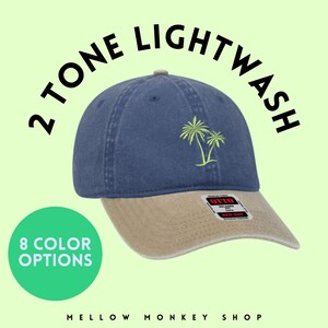 May include: A two-tone lightwash baseball cap with a brown brim and a blue crown. The cap features an embroidered palm tree design and a small label with the text "OTTO" on the front.