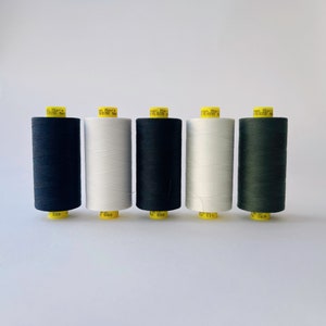 Peut inclure: Cinq bobines de fil noir, blanc, noir, blanc et vert. Les bobines sont étiquetées "Mara Polyester No."