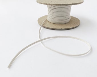 May include: A spool of white elastic cord on a cardboard spool. The cord is wound tightly around the spool and is ready to be used for crafting or sewing projects.