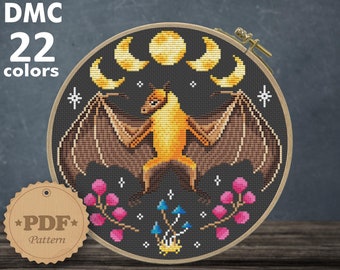 Puede incluir: Un patrón de punto de cruz con un murciélago amarillo con alas marrones, rodeado de lunas, estrellas y flores rosas y azules. El patrón está diseñado para tela Aida de 14 hilos y mide 7,86 x 8,00 pulgadas (19,96 x 20,32 cm).