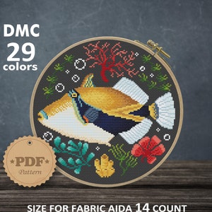 May include: A cross-stitch pattern of a colorful triggerfish surrounded by coral and seaweed. The pattern is in a round embroidery hoop and is labeled "DMC 29 colors" and "PDF Pattern". The size of the pattern is 19.78 x 19.96 cm or 109 x 110 stitches, which is 7.79 x 7.86 inches.
