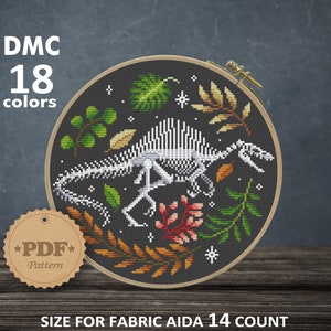 May include: A black and white cross-stitch pattern of a dinosaur skeleton surrounded by green, red and yellow leaves. The pattern is in a round hoop and is labelled "DMC 18 colours" and "PDF Pattern". The pattern is for Aida 14 count fabric and measures 8.00 x 7.50 inches or 20.32 x 19.05 cm.