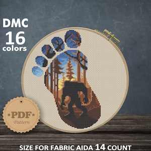 May include: Cross-stitch pattern featuring a Bigfoot footprint design with a forest scene inside. The embroidery is in a wooden hoop. The text "DMC 16 colors" is visible. The size is 5.57 x 8.14 inches.