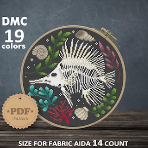 May include: A cross-stitch pattern featuring a fish skeleton with colorful coral and seaweed on a black background. The pattern is in a round embroidery hoop and is labeled "DMC 19 colors" and "PDF Pattern". The size of the pattern is 19.96 x 19.96 cm or 7.86 x 7.86 inches.