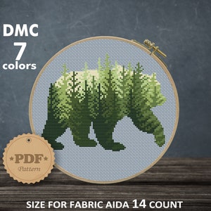 May include: Cross stitch pattern of a bear silhouette with a forest inside. The pattern is for Aida 14 count fabric and measures 83 x 66 stitches, or 5.93 x 4.71 inches. The pattern requires 7 DMC colors.