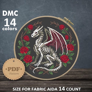 May include: Cross-stitch pattern featuring a skeletal dragon with red wings and roses, framed in a wooden hoop. The text reads "DMC 14 colors" and "PDF Pattern". The finished size is 7.86 x 7.36 inches.