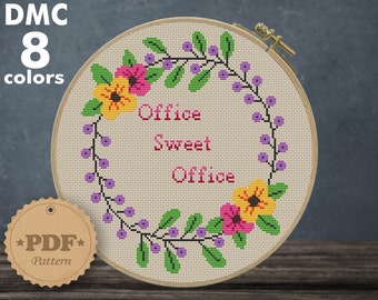 May include: A cross-stitch pattern featuring a floral wreath with the text "Office Sweet Office" in a 7.43 x 8.57 inch hoop. The pattern is designed for 14 count Aida fabric and requires 8 DMC colors.