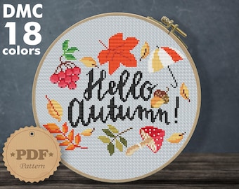 May include: A cross-stitch pattern featuring the text "Hello Autumn!" surrounded by autumn leaves, berries, acorns, and mushrooms. The pattern is designed for Aida 14 count fabric and measures 7.50 x 6.51 inches or 19.05 x 15.78 cm.