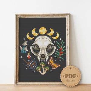 May include: Cross stitch pattern featuring a white animal skull with a crescent moon and stars, surrounded by mushrooms, berries, and a butterfly on a black background. The pattern is available as a PDF download.
