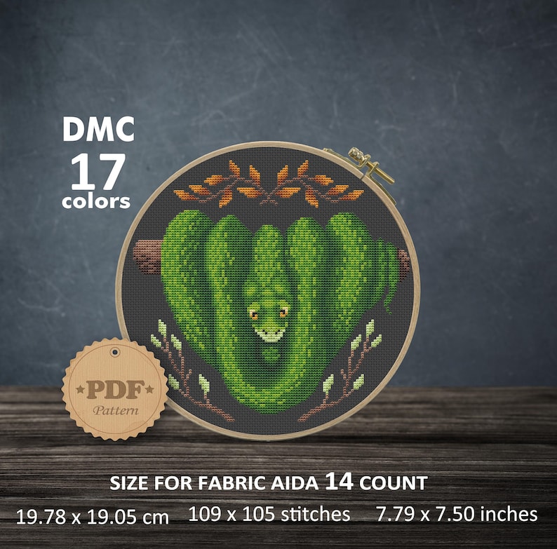 May include: Cross stitch pattern featuring a green snake curled up in a heart shape with brown branches and green leaves on a dark gray background. The pattern is for Aida 14 count fabric and measures 7.79 x 7.50 inches or 109 x 105 stitches. The pattern requires 17 DMC colors.