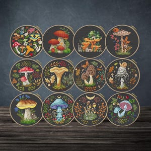 May include: A collection of twelve circular embroidery hoops, each displaying a unique mushroom design. The designs feature various mushroom illustrations in shades of red, orange, and blue, set against a dark grey backdrop, with leaves and other natural elements.