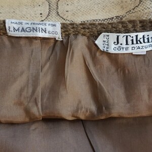 May include: Close-up of the interior of a garment, featuring two tags. One tag reads "MADE IN FRANCE FOR I. MAGNIN & CO." The other tag reads "J. Tiktiner C&Ocirc;TE D'AZUR - NICE". The lining is a light brown color.
