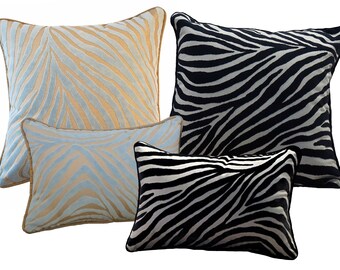 May include: Four decorative throw pillows with a zebra print pattern. The pillows are in various sizes and colors, including black, white, light blue, and tan.