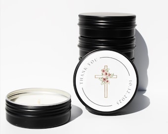 May include: Black metal candle tins, one open and several stacked, with a white label featuring a gold cross adorned with pink flowers. The label also includes the text "THANK YOU" and the date "10.12.2025".