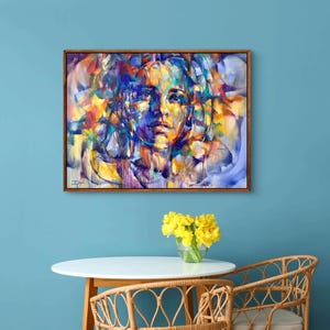 Pu&ograve; includere: Dipinto astratto di un viso di donna su uno sfondo colorato. Il dipinto &egrave; incorniciato in una cornice di legno marrone ed &egrave; appeso a una parete blu.