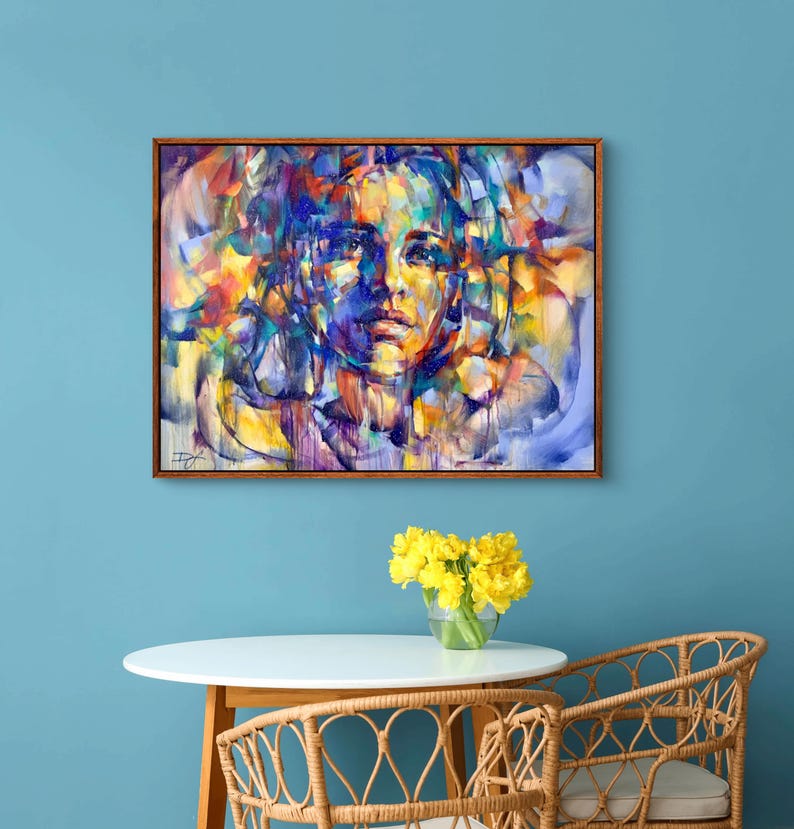 Pu&ograve; includere: Dipinto astratto di un viso di donna su uno sfondo colorato. Il dipinto &egrave; incorniciato in una cornice di legno marrone ed &egrave; appeso a una parete blu.