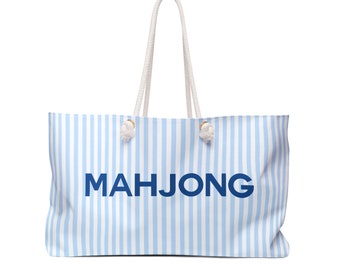 May include: A large tote bag with a light blue and white striped pattern. The word "MAHJONG" is printed in navy blue across the front. The bag has white rope handles.
