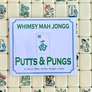以下が含まれることがあります： 緑色の文字で「WHIMSY MAH JONGG」と「PUTTS & PUNGS」と書かれた、青い縁取りのカード。カードは、さまざまなイラストが描かれた白い麻雀牌を背景にしています。