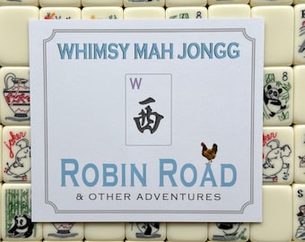 May include: A white square card with a gray border featuring the text WHIMSY MAH JONGG, ROBIN ROAD & OTHER ADVENTURES, a West wind tile illustration, and a small chicken image, placed over a background of cream-colored Mah Jongg tiles.