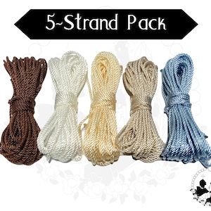May include: Five skeins of rope in shades of brown, white, cream, beige, and blue. The text "5-Strand Pack" is displayed above the ropes. The ropes are tightly wound and appear to be made of a smooth, shiny material. Ideal for crafts and DIY projects.