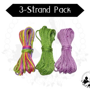 May include: A pack of three strands of cord, one green, one purple, and one with pink, yellow, and green stripes. The pack is labelled "3-Strand Pack".
