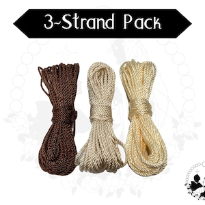 May include: Three spools of cord for making rosaries. The cords are brown, cream, and white.