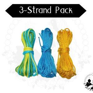 May include: Three bundles of rope in turquoise and yellow, blue, and gold. The text "3-Strand Pack" is displayed in a black banner above the ropes. The ropes are tightly wound and ready for use.