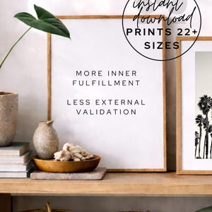 May include: A framed print with the text "MORE INNER FULFILLMENT, LESS EXTERNAL VALIDATION" is displayed on a wooden shelf. The print is in a light brown frame. A circular graphic reads "instant download, PRINTS 22+ SIZES".