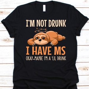 May include: Black t-shirt with the text "I'M NOT DRUNK I HAVE MS OKAY--MAYBE I'M A 'LIL DRUNK" and a cartoon sloth illustration. The sloth is brown and orange with a halo above its head.