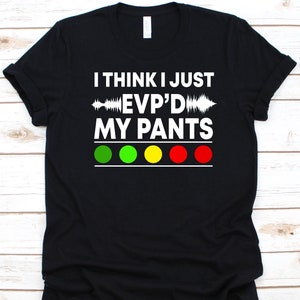 May include: Black t-shirt with the text "I THINK I JUST EVP'D MY PANTS" in white. The design features a sound wave graphic and four coloured circles: green, yellow, and red. A humorous, novelty tee.