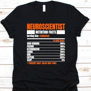 May include: Black t-shirt with orange text that reads "NEUROSCIENTIST NUTRITION FACTS." The shirt lists daily values for hard work, passion, determination, caring, kindness, caffeine, and sleep. The serving size is listed as unlimited.