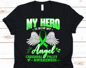 Op de afbeelding: Zwart T-shirt met de tekst "MY HERO is now my Angel CEREBRAL PALSY AWARENESS" in groen en wit. Het ontwerp bevat engelenvleugels en een groen bewustzijns lint.