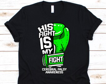 May include: Black t-shirt with a green boxing glove graphic and the text "HIS FIGHT IS MY FIGHT" in white. The shirt also includes the text "CEREBRAL PALSY AWARENESS" in white. The design is centered on the front of the shirt.