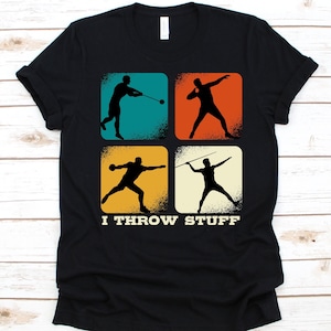 May include: Black t-shirt featuring four colored squares with silhouettes of athletes throwing a hammer, shot put, discus, and javelin. The text "I THROW STUFF" is printed below the squares.
