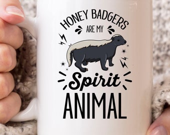 May include: White ceramic mug with the text "HONEY BADGERS ARE MY SPIRIT ANIMAL" and a graphic of a honey badger. The honey badger is black and gray. The mug has a white handle.