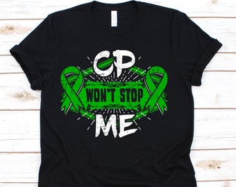 Peut inclure: T-shirt noir avec un motif vert et blanc. Le motif comprend les lettres "CP" au-dessus des mots "WON'T STOP ME", avec des rubans de sensibilisation verts. Le graphisme a un aspect vieilli et vintage.