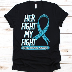 May include: Black t-shirt with the text "HER FIGHT MY FIGHT" in white and light blue, along with a teal awareness ribbon. The bottom of the shirt reads "DIGEORGE SYNDROME AWARENESS".