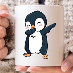May include: White ceramic mug featuring a cartoon penguin in a dabbing pose. The penguin is black and white with an orange beak and feet. The mug has a handle and is held by a person.