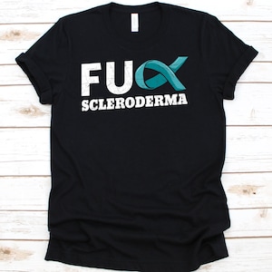 Könnte beinhalten: Schwarzes T-Shirt mit dem weißen Text "FU SCLERODERMA" und einer tealfarbenen Schleifengrafik. Das Shirt hat einen Rundhalsausschnitt und ist aus weichem Material.