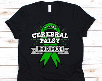 Peut inclure: T-shirt noir avec un motif de ruban vert et le texte "I MAKE CEREBRAL PALSY LOOK GOOD". Le motif comprend du texte blanc et une bannière grise. Le t-shirt est fait d'une matière douce.