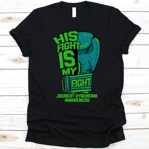 May include: Black t-shirt with a green and teal boxing glove graphic. The text reads "HIS FIGHT IS MY FIGHT" and "JOUBERT SYNDROME AWARENESS" in green. The shirt is made of a soft material.