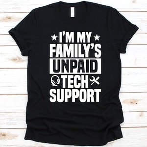 Peut inclure: T-shirt noir avec texte blanc : « I'M MY FAMILY'S UNPAID TECH SUPPORT ». Le motif comprend une étoile, un casque et une clé. Le t-shirt est en matière souple et a un col rond classique.