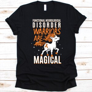 May include: Black t-shirt featuring the text "FUNCTIONAL NEUROLOGICAL DISORDER WARRIORS ARE MAGICAL" and a white unicorn with an orange mane and tail. The unicorn has an orange awareness ribbon. The text and unicorn are in orange and white.