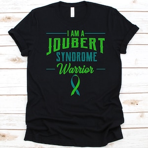 May include: Black t-shirt with the text "I AM A JOUBERT SYNDROME Warrior" in green and teal. A teal ribbon is below the text. The shirt is made of a soft material.