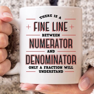 May include: White ceramic mug with the text "THERE IS A FINE LINE BETWEEN NUMERATOR AND DENOMINATOR ONLY A FRACTION WILL UNDERSTAND" in black and red lettering. The mug has a curved handle.