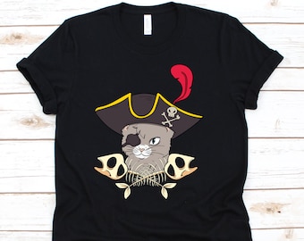 May include: Black t-shirt featuring a gray cat wearing a pirate hat with a red feather and an eye patch. The cat is surrounded by fish bones and skull-shaped designs. The shirt is made of a soft material.