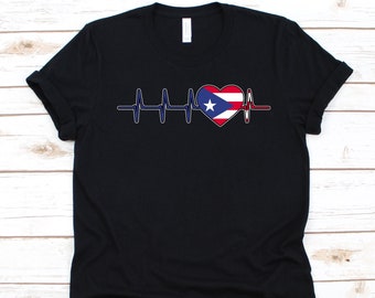 May include: Black t-shirt featuring a heartbeat design with a heart-shaped Puerto Rican flag in the center. The flag design includes red and white stripes and a blue star on a white triangle.