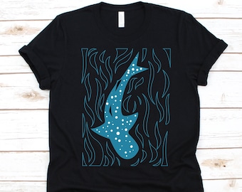 May include: Black t-shirt featuring a teal whale shark design with white spots. The whale shark is surrounded by teal flame-like shapes. The shirt is made of a soft material and has a classic crew neck.