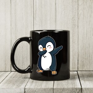 May include: Black ceramic mug featuring a cartoon penguin in a dabbing pose. The penguin is colored in shades of blue, white, and orange, with a cheerful expression. The mug has a curved handle and a glossy finish, suitable for hot or cold beverages.